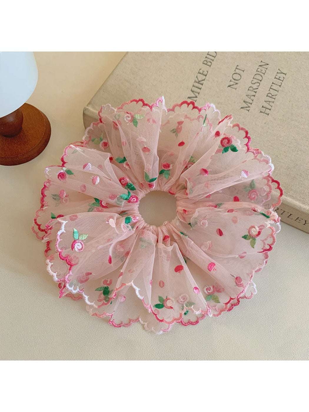 Pink ruffled scrunchie styled in a ponytail on model with dark hair