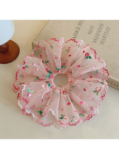 Pink ruffled scrunchie styled in a ponytail on model with dark hair