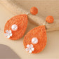 Pair of Earedge chic teardrop drop earrings laid flat on wooden surface