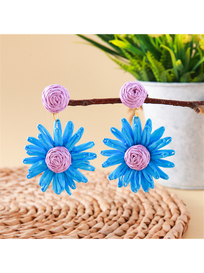 Pair of lightweight raffia stud earrings with daisy flower design on beige fabric