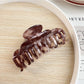 Beau double row crescent claw clip resting on a white surface