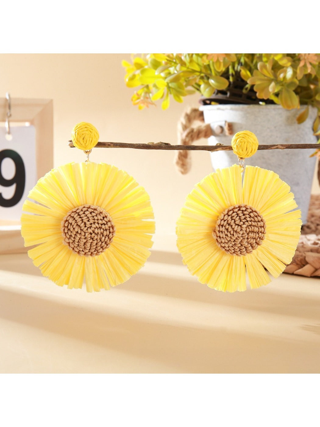 Side view of a raffia sunflower earring showing the woven texture and earring post