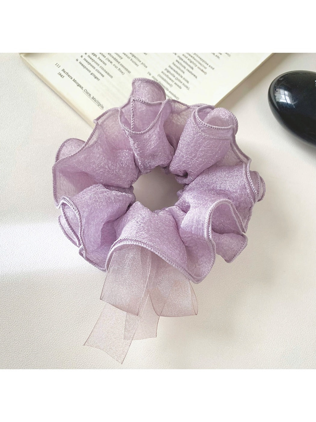 Purple bow scrunchie styled in a ponytail on a model with dark hair