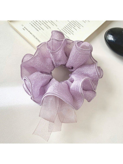 Purple bow scrunchie styled in a ponytail on a model with dark hair