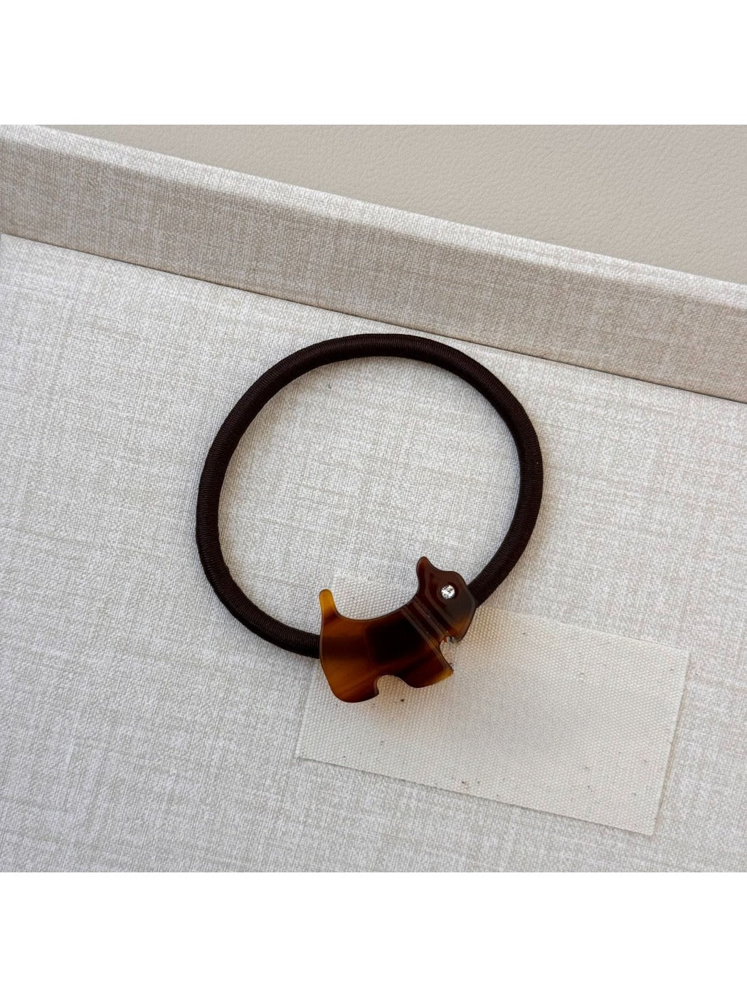 Gifty hair tie with cartoon puppy embellishment held between fingers