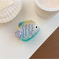 Beau colorful fish claw clip with blue, orange, and white hues on neutral background