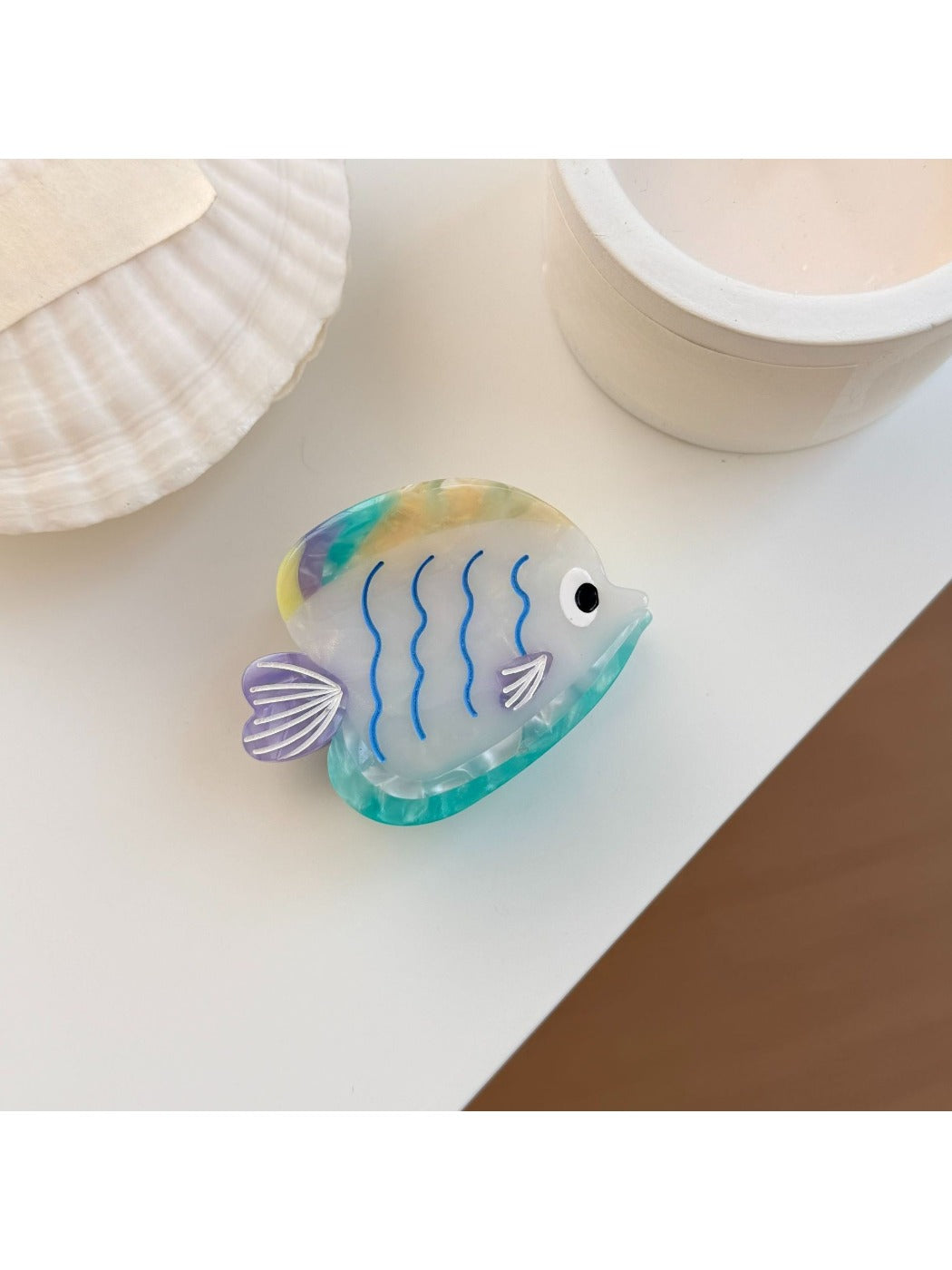 Beau colorful fish claw clip with blue, orange, and white hues on neutral background