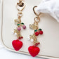 Cherry heart charm keychain with red enamel and gold-tone metal on a white background