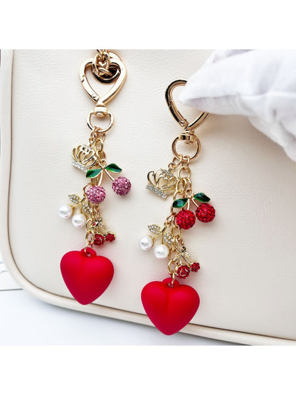 Cherry heart charm keychain with red enamel and gold-tone metal on a white background