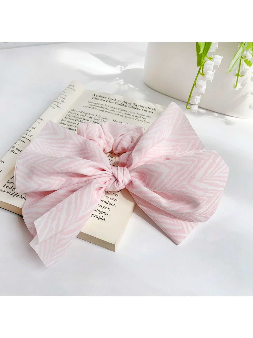 Striped bow scrunchie in beige and white stripes on a neutral background