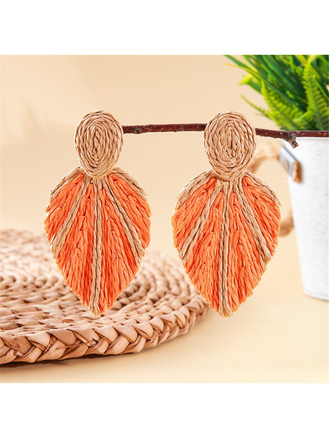 Model wearing Earedge raffia woven leaf shaped earrings with natural makeup