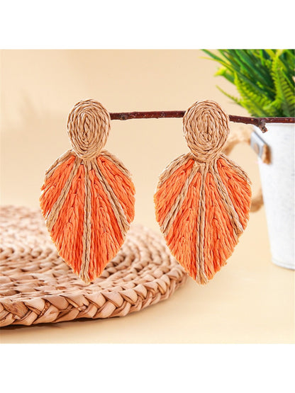 Model wearing Earedge raffia woven leaf shaped earrings with natural makeup
