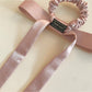Flat lay of the bow embellished hair tie showing its elastic band and fabric texture