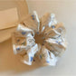 Gifty satin floral print scrunchie displayed on a white surface showing fabric texture