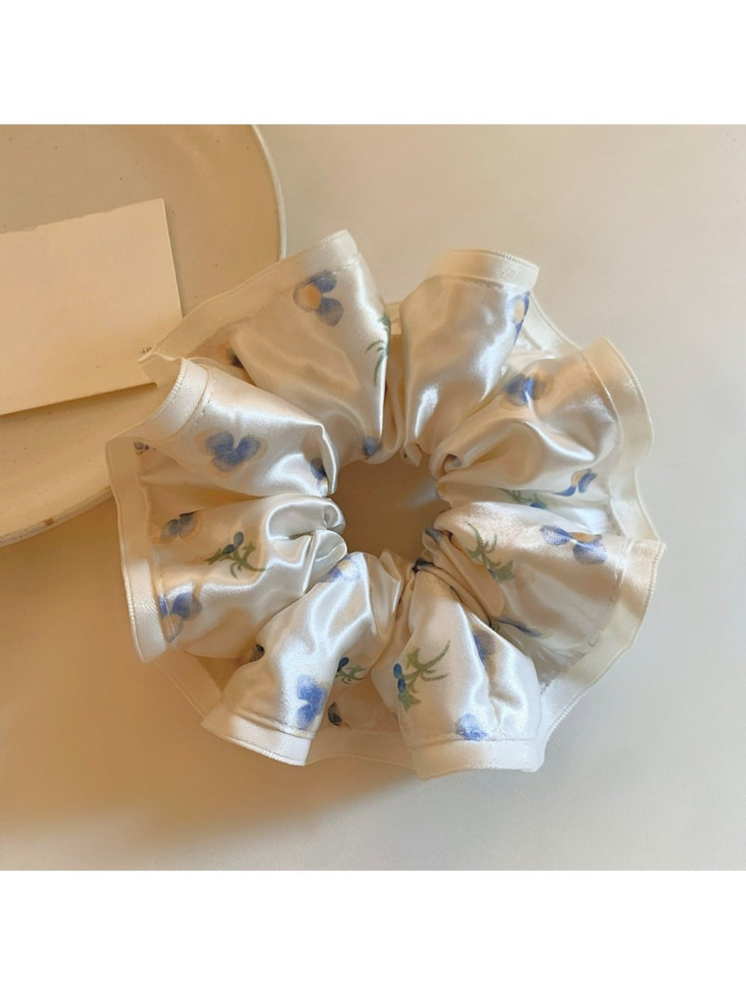 Gifty satin floral print scrunchie displayed on a white surface showing fabric texture