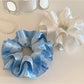 Gifty satin ruffle scrunchie in pastel purple laid flat to show ruffle detail
