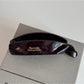 Beau minimalist stick hair clip in matte black resting on wooden surface