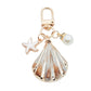 Gold conch keychain attached to a set of keys on a wooden surface