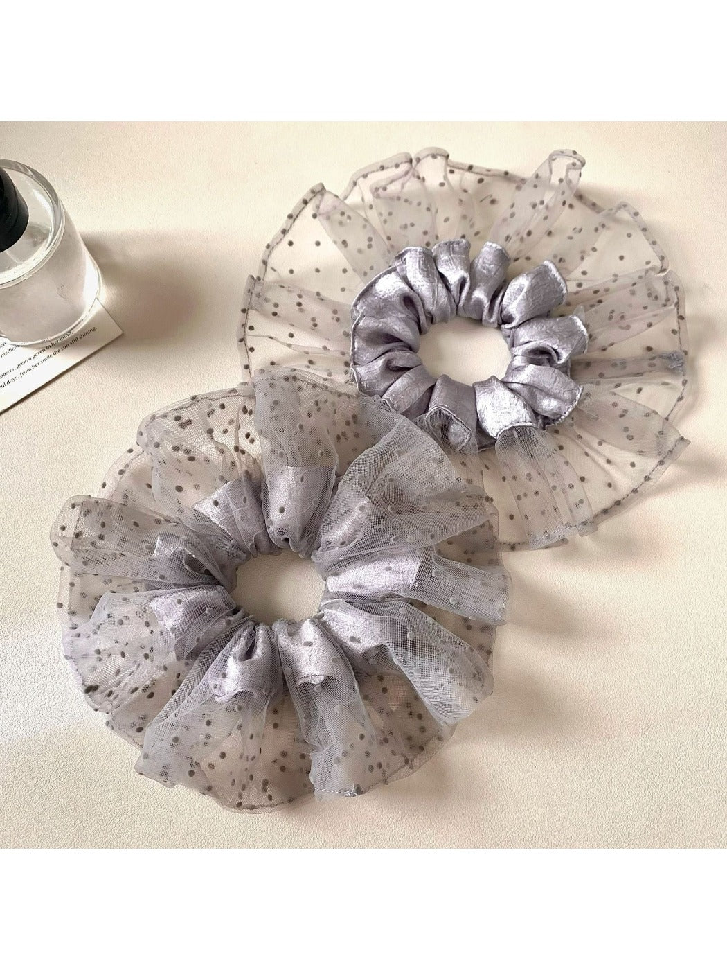 Gray mesh scrunchie with black polka dots on a white background