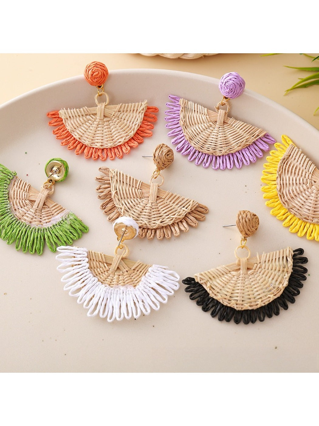 Earedge raffia fan shaped drop earrings displayed hanging on a stand