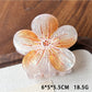 Beau claw clip with lifelike flower design resting on natural wood background