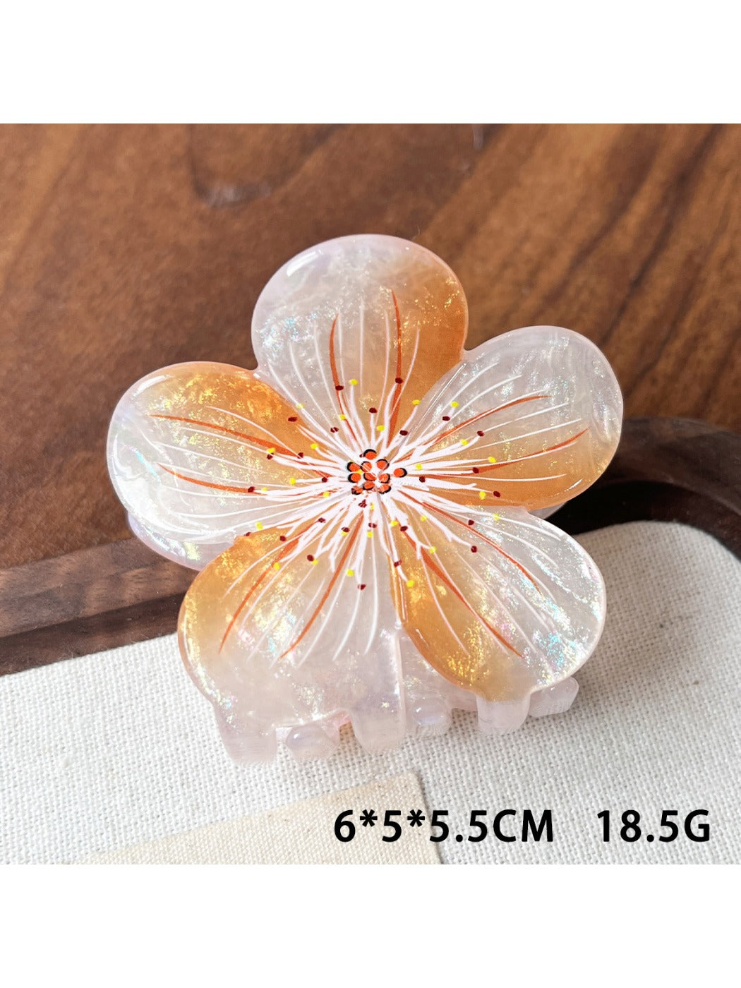 Beau claw clip with lifelike flower design resting on natural wood background