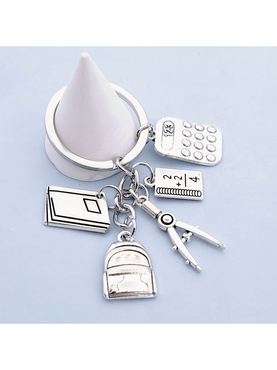 Alloy backpack book keychain displayed with other small accessories on a table