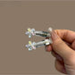 Hand holding a bright, modern minimalist hair clip against a plain backdrop