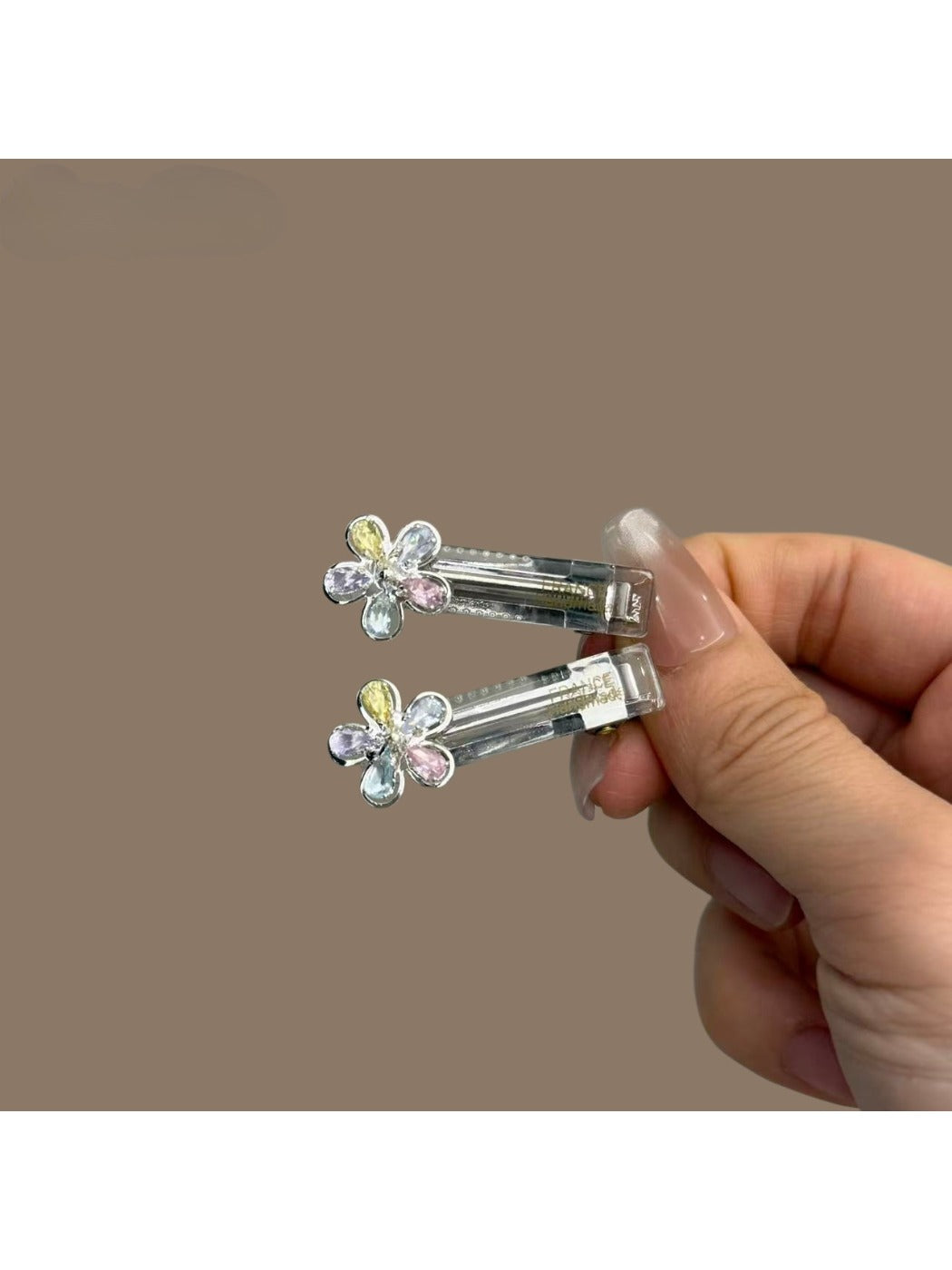 Hand holding a bright, modern minimalist hair clip against a plain backdrop