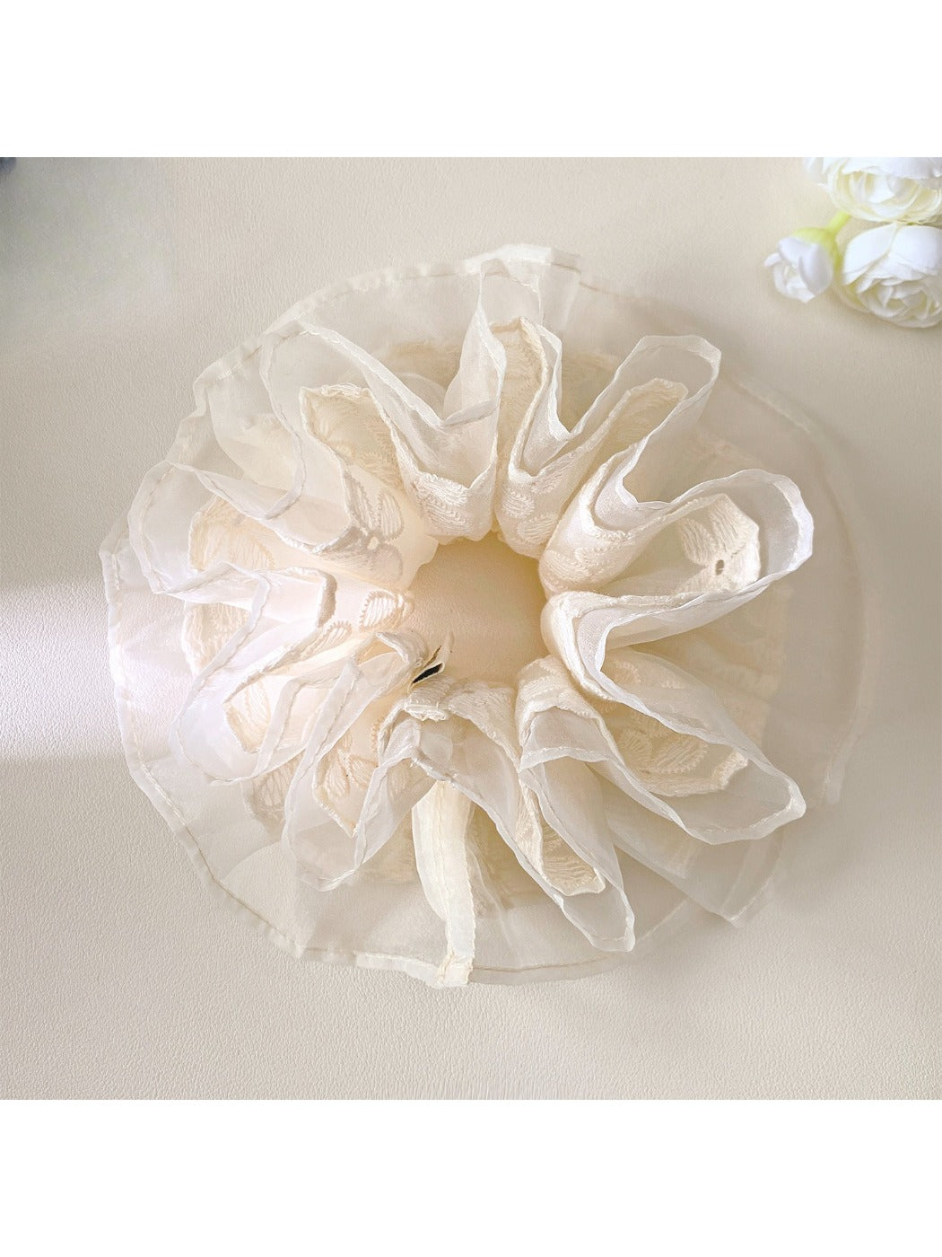 White lace scrunchie styled on a model's wrist with soft lighting