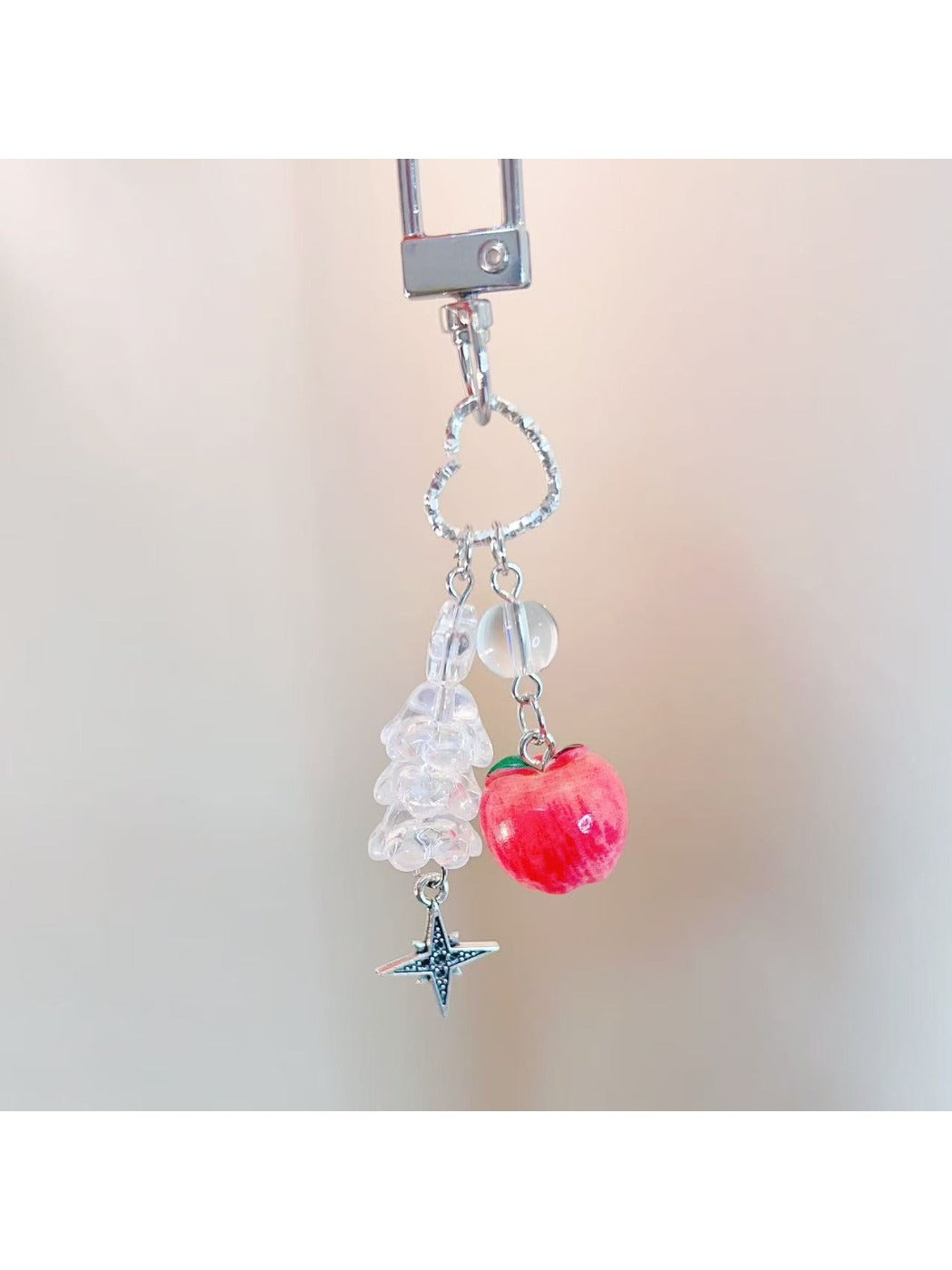 Mini apple keychain hanging from a set of keys on a wooden surface