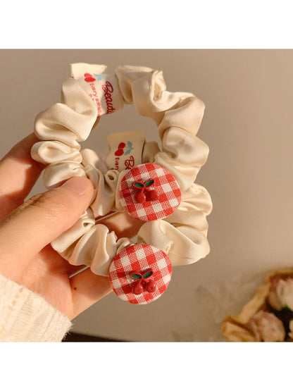 Gifty Sweet Plaid Cherry Hair Tie styled on a ponytail with visible cherry charm