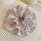 Purple floral scrunchie worn on a wrist as a fashion accessory