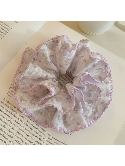 Purple floral scrunchie worn on a wrist as a fashion accessory