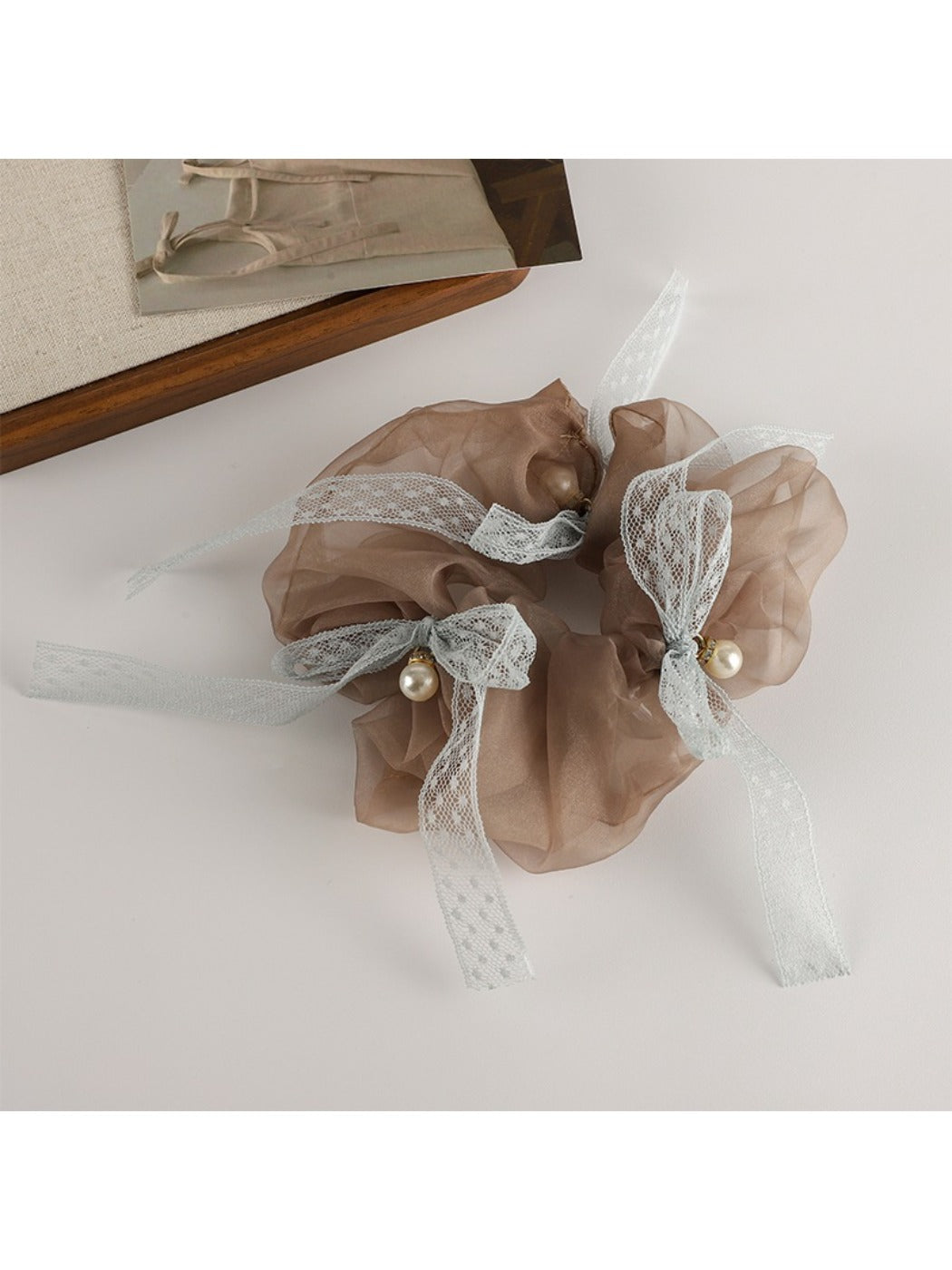 Gifty Sweet Bow Accented Ruched Scrunchie held in hand against neutral background