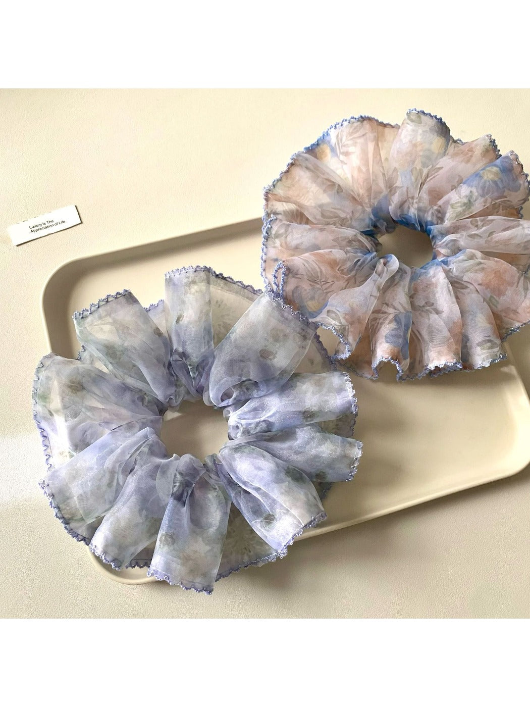 Close-up of a beige scrunchie with subtle vintage floral print