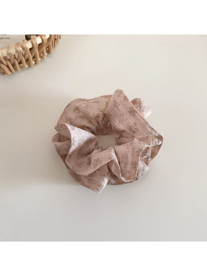 Gifty floral scrunchie paired with matching hair accessories on a wooden surface