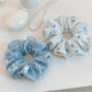 Blue scrunchie with white bow print on a plain background
