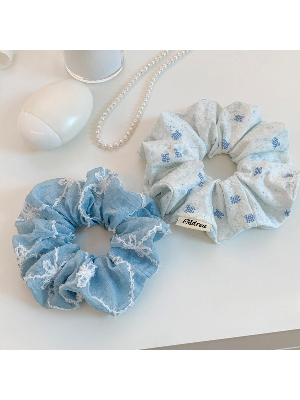 Blue scrunchie with white bow print on a plain background
