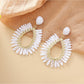 Close-up of earring hook and woven raffia detail on teardrop hollow earring