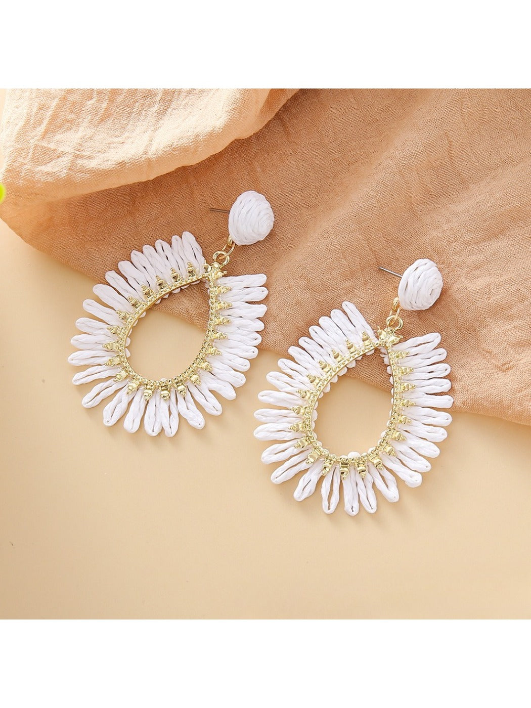 Close-up of earring hook and woven raffia detail on teardrop hollow earring
