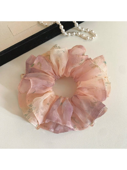 Gifty scrunchie styled on a wrist, displaying its vibrant sweet print and layered fabric