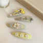 Yellow tiny floral hair clip with small white and orange flowers on a light background