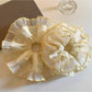 Close-up of yellow pleated fabric and floral pattern on scrunchie