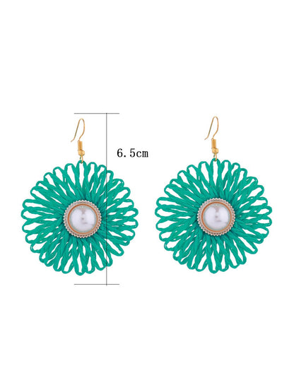 Pair of Earedge raffia woven flower-shaped earrings displayed on white background
