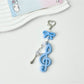 Hand holding the Keypus cute music note keychain against a blurred background