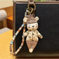 Bear keychain with a trendy hat shown next to keys