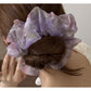 Multi color tulle scrunchie styled on a wrist with soft pastel colors