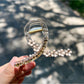 Beau floral cross hair claw clip displayed on a wooden surface with natural lighting