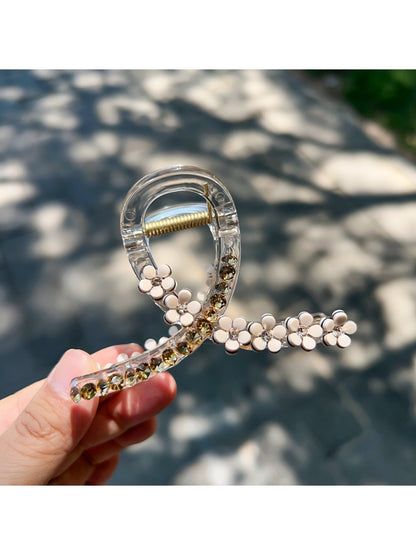 Beau floral cross hair claw clip displayed on a wooden surface with natural lighting